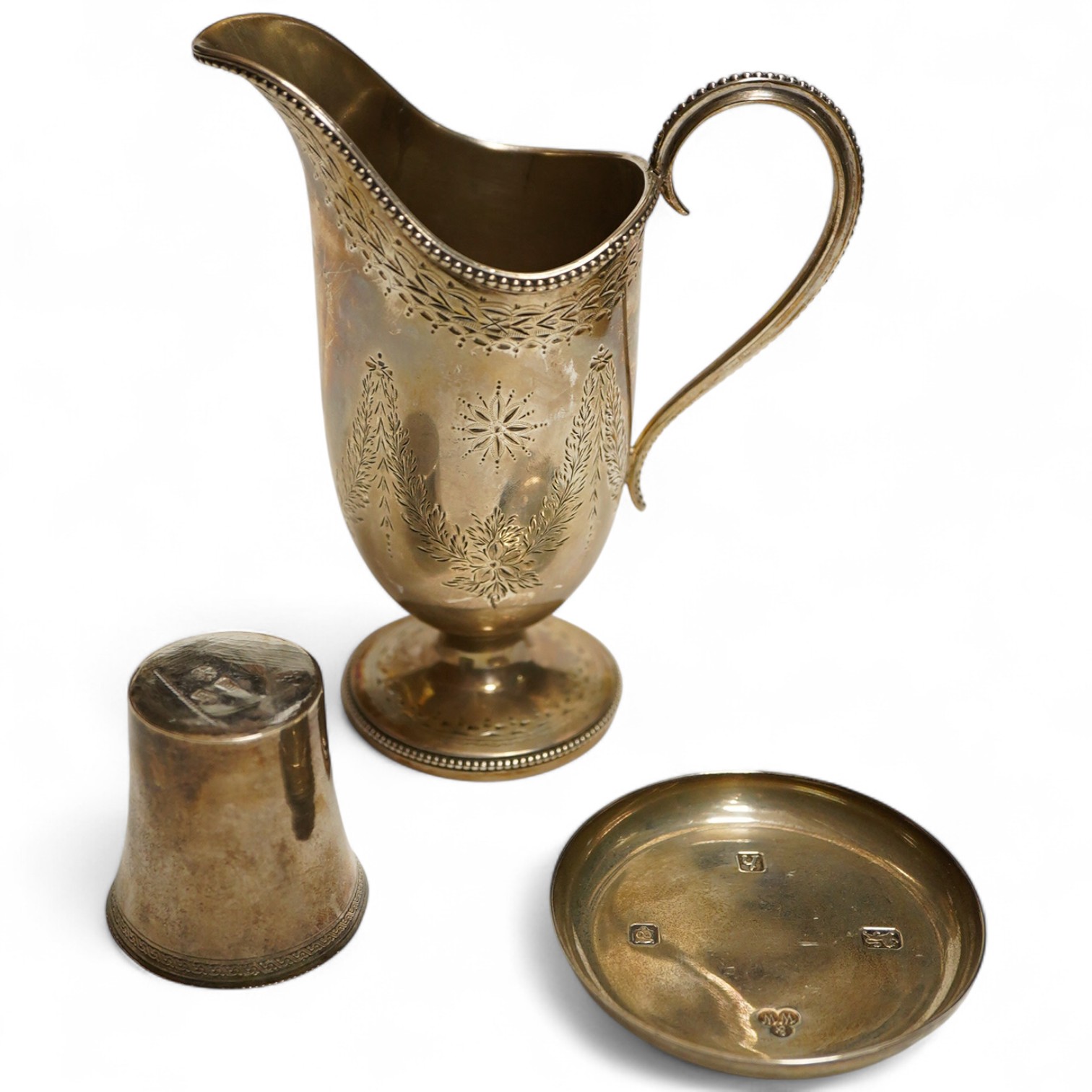 A Victorian silver cream jug, London, 1874, Robert Harper, of helmet form with bright cut decoration, together with a small continental beaker and an Elizabeth II pin dish with feature hallmarks, weight approx 8.56ozt (3